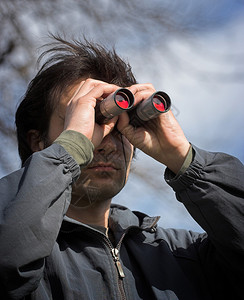 男人通过双筒望远镜看图片