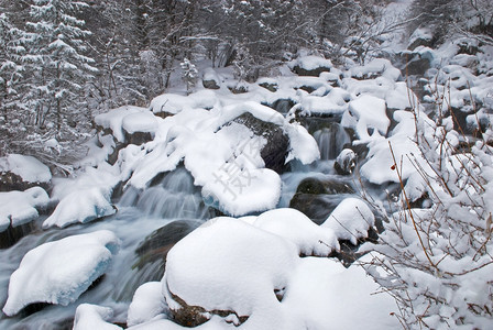 在降雪期间的冬天山小河图片