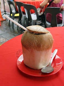 用勺子在红桌上的新鲜椰子汁图片
