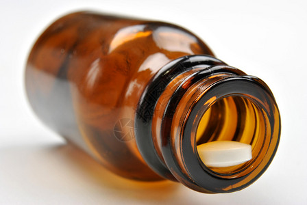 棕色药瓶和一粒白色药丸背景图片