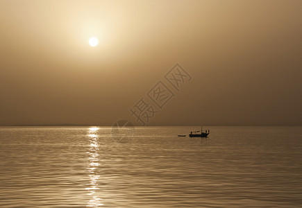 日落时独自在海上的小型传统捕鱼船图片