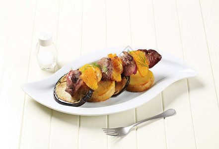 烤土豆和茄子片上的牛肉烤串图片