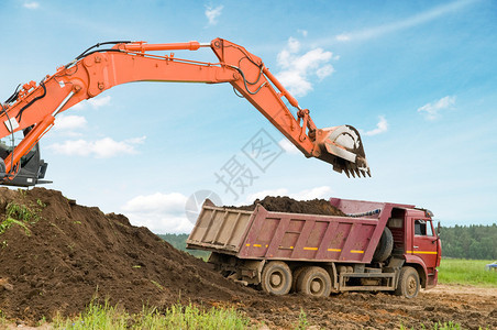 重型挖土机装载倾卸式卡车在蓝天图片