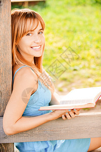 美丽的年轻女子读书关于木制扶手图片
