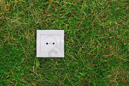 绿色能源概念草地上的电源插座图片