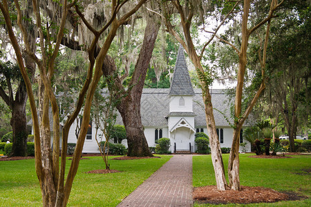 一座古老的白色木制教堂经过绿色草坪和砖砌的人行道图片