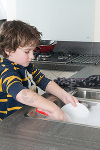 在现代厨房里洗碗的男孩图片