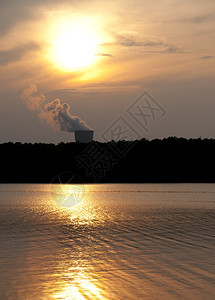 日落时湖上的一座运转良好的核电站图片