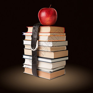 许多书堆满了苹果和黑色皮带图片