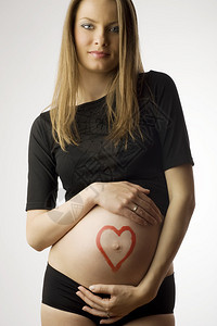 怀着心跳的美丽孕妇露出肚子并用心脏图片