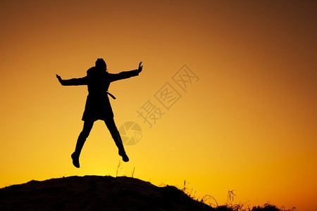 冬天日落时年轻女子站在山顶图片