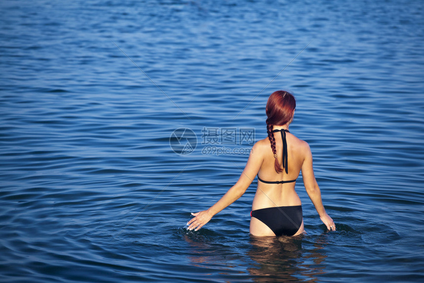 美丽的年轻女子在海上泼水夏天图片