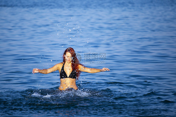 美丽的年轻女子在海上泼水夏天图片