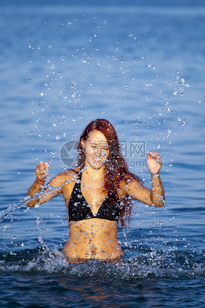 美丽的年轻女子在海上泼水夏天图片