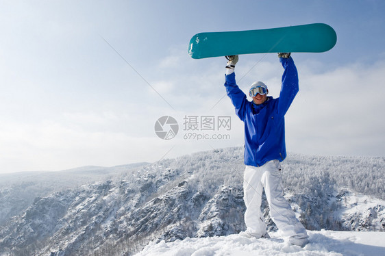 快乐的运动员肖像与站在山顶上的滑雪板图片