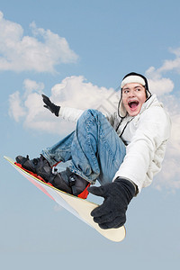雪板跳在天空背景上的小男孩的肖像图片