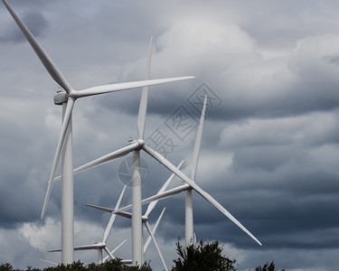 乌云密布的天空下的一组风车或涡轮机背景图片