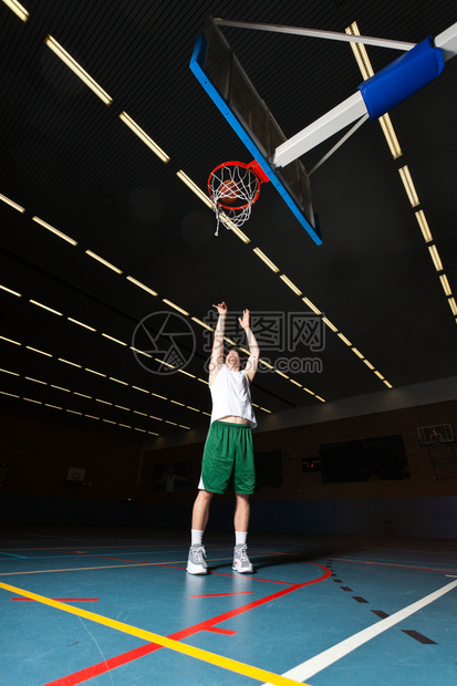 坚强健康的年轻人在健身房室内打篮球身穿白衬衫和绿色短裤图片