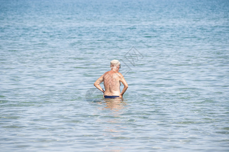 老人穿着泳装走在海面上图片