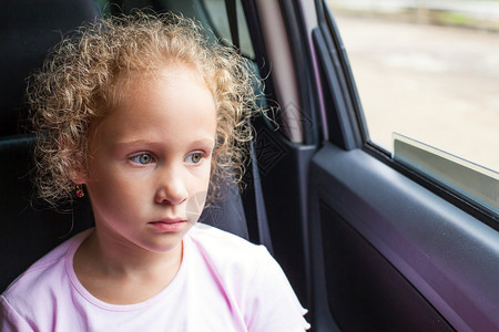 可怜的小女孩坐在车窗图片