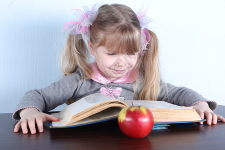 有苹果和蓝白背景书籍的小姑娘图片