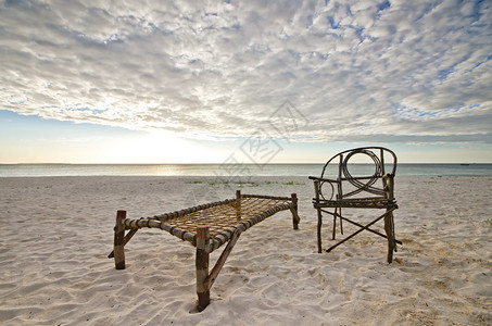 老竹子座椅和露营床坐在桑迪海滩上海边把太阳定在戏图片