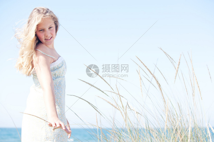 年轻女孩站在蓝天的对面海边有长草转动图片