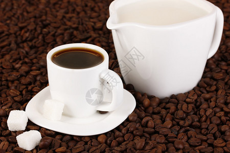 一杯浓咖啡和咖啡豆上的甜奶油特写图片