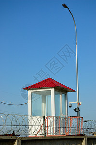 蓝天背景下带刺铁丝网的警卫塔背景图片
