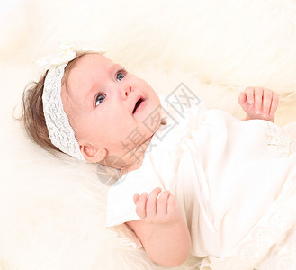 穿着白色连衣裙的可爱女婴躺在床上图片