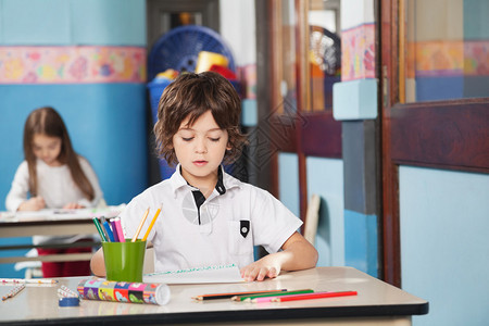 幼稚园有彩色铅笔和绘画纸的男孩背景图片