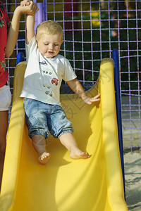 小男孩在公园里儿童滑幻灯片上的小孩图片