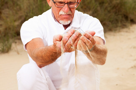 退休的老人手拿沙子图片