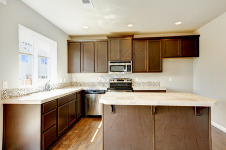 新的家庭厨房内部有深棕色橱柜和硬木地板图片