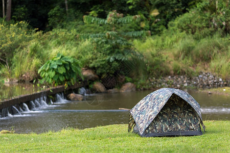 迷彩纹在池塘附近的热带野生环境中的一个帐篷背景