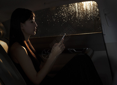 坐在车里用她的手机发短信的女人背景图片