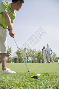 高尔夫果岭在高尔夫球场打球的年轻男子背景中背景