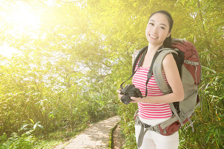 带着相机笑着的亚洲旅行女孩在户外路上看着你图片