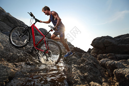 青年运动员骑自行车穿越水障图片