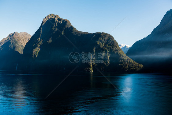 清晨航行到新西兰南岛的密尔福德湾当太阳升起在山上时图片