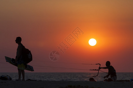 风筝冲浪者在日落时航行的剪影图片