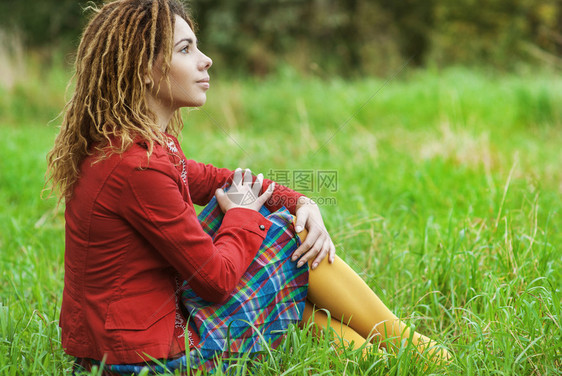 年轻悲伤的美女穿着红色礼服的毛衣坐在图片