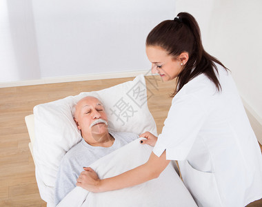 女医生在诊所用毛毯覆盖老年男子的高图片