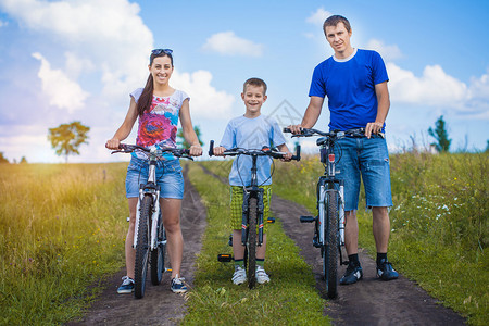幸福的一家人在夏日的田野里骑行图片