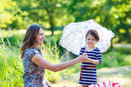 母亲和可爱的小女儿带着雨伞在图片
