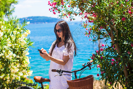 在美丽的海湾上用手机照相的游客女图片