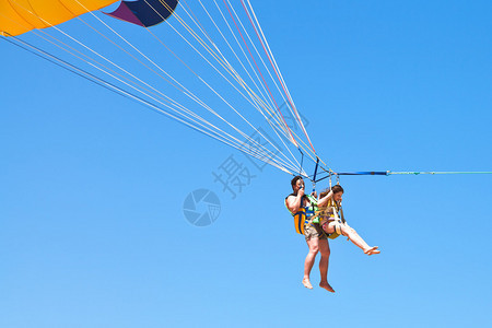 夏日蓝天下男人和女孩在降落伞上滑翔伞图片