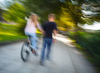 男女骑自行车穿过秋巷故意运动模糊不清图片