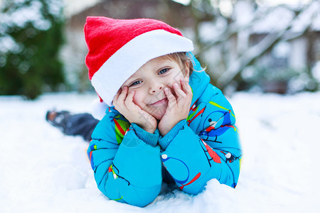 快乐的小孩男等待圣诞塔帽躺在雪上在冬图片