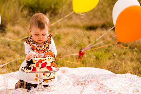 婴儿女孩用美食蛋糕和气球庆祝她第图片